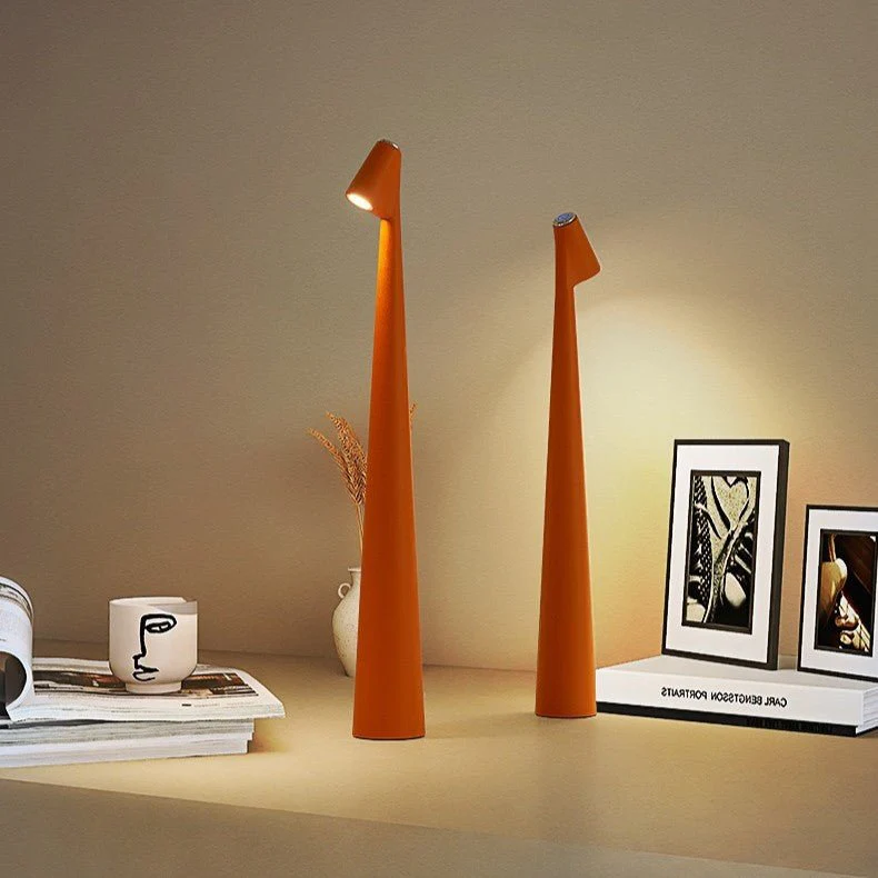 Two orange table lamps on a surface with books and a cup in the background.