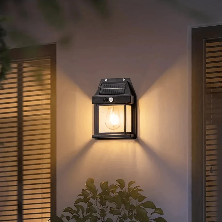Solar wall light fixture on a wall with a warm glow, surrounded by wooden shutters and greenery.