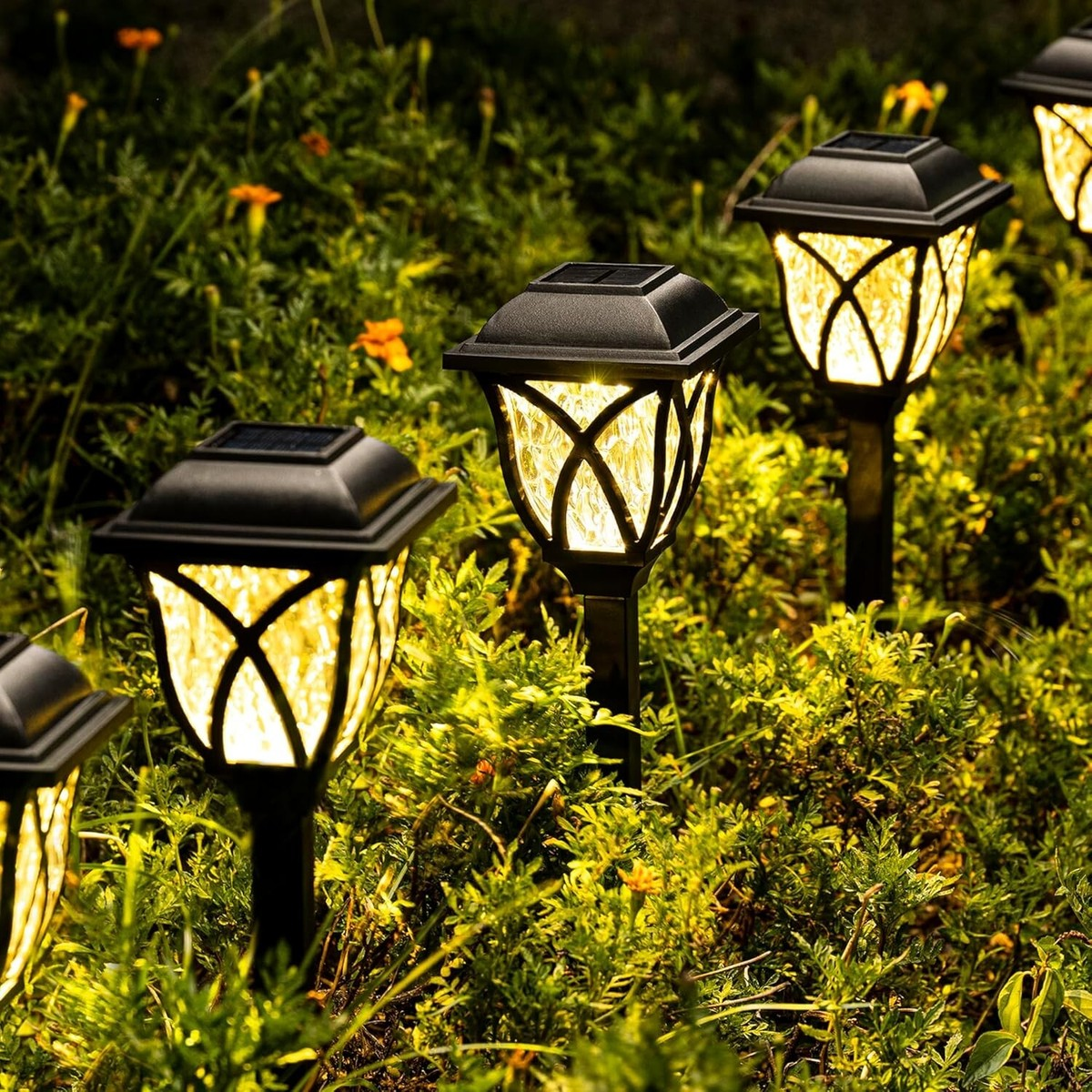 Solar-powered garden lights illuminating a grassy area with flowers.