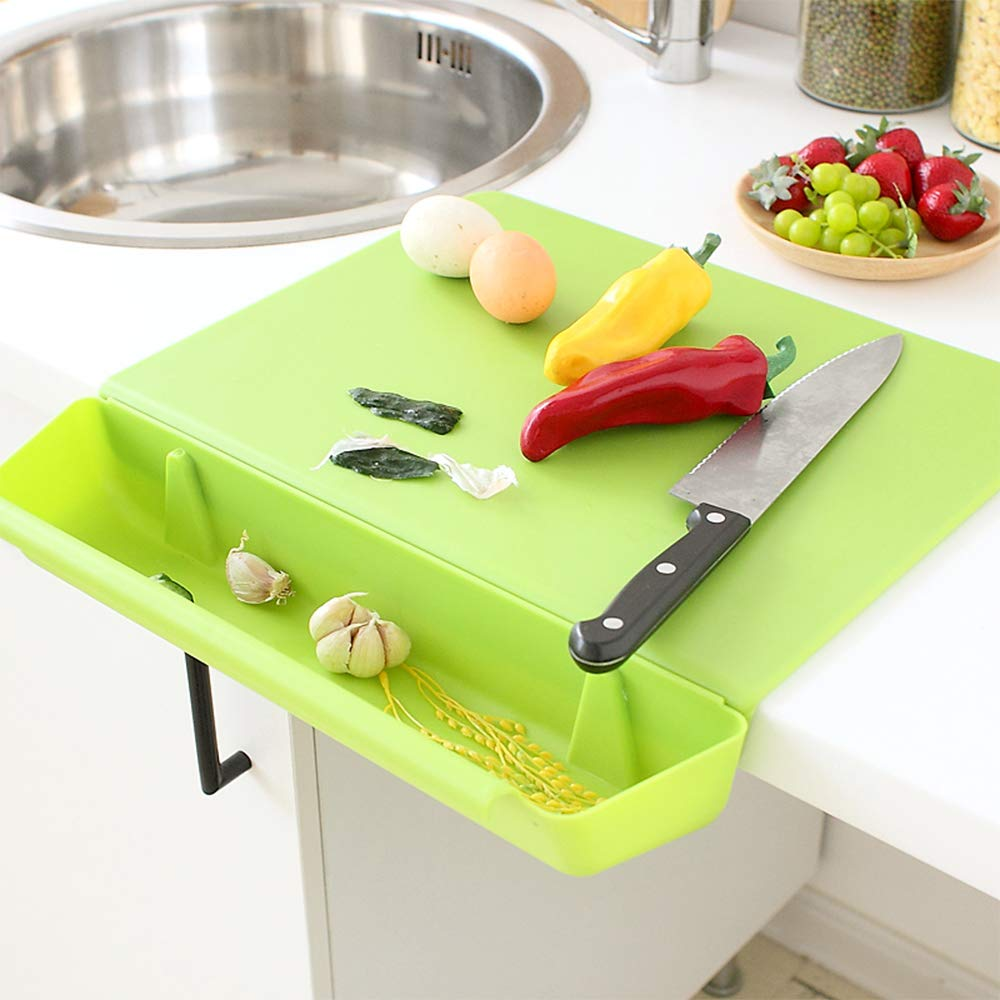 Green cutting board with vegetables and a knife on a kitchen counter