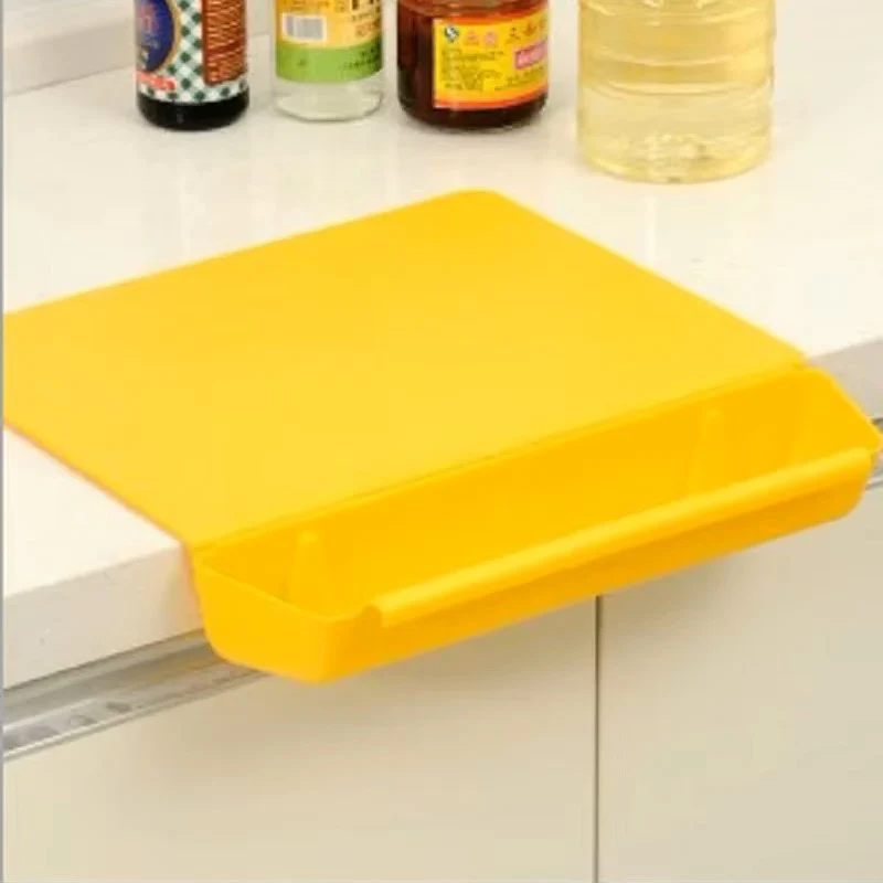 Yellow cutting board attached to a kitchen cabinet with bottles in the background