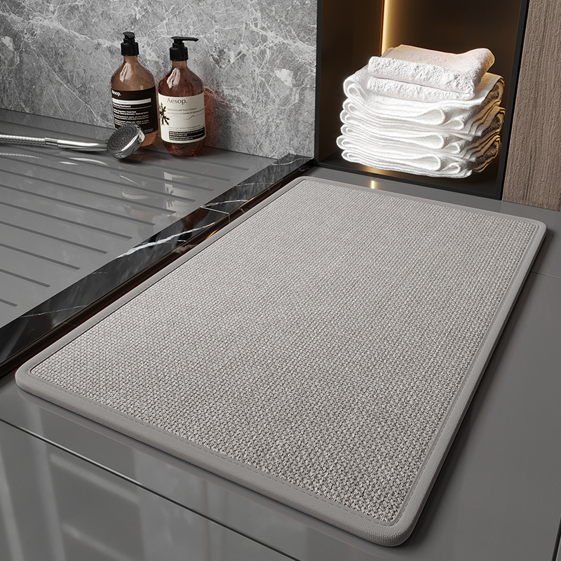 Gray textured mat on a kitchen counter with towels and bottles in the background