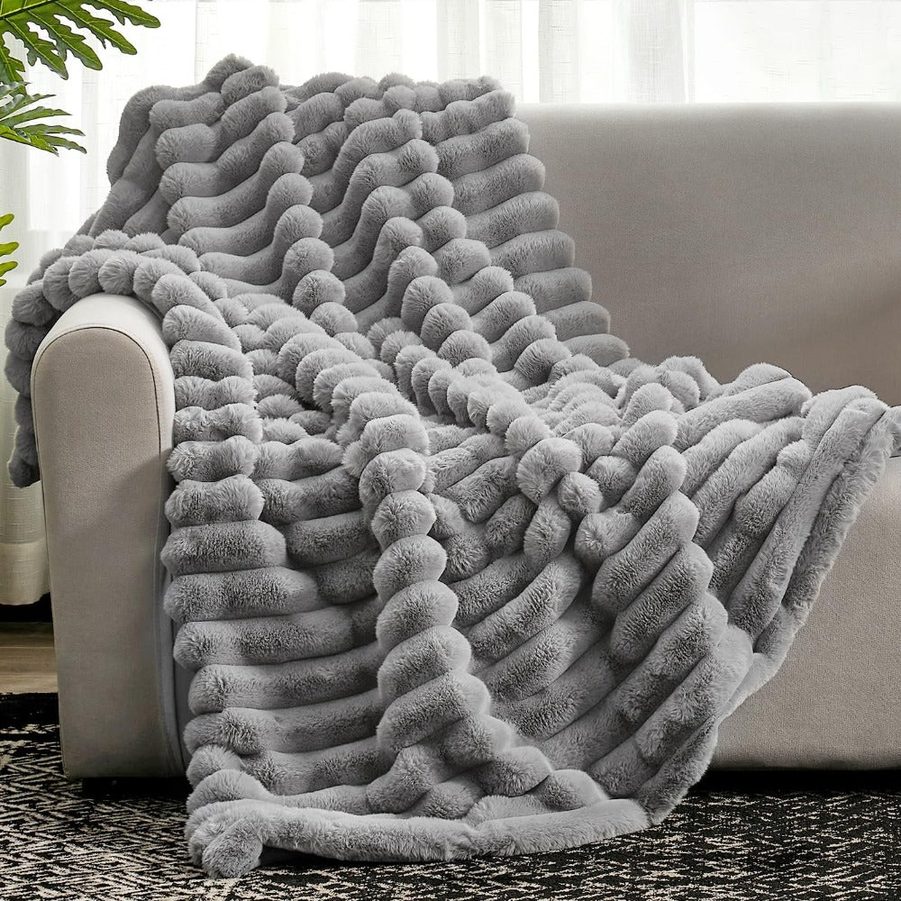 Gray textured blanket draped over a couch in a living room setting.