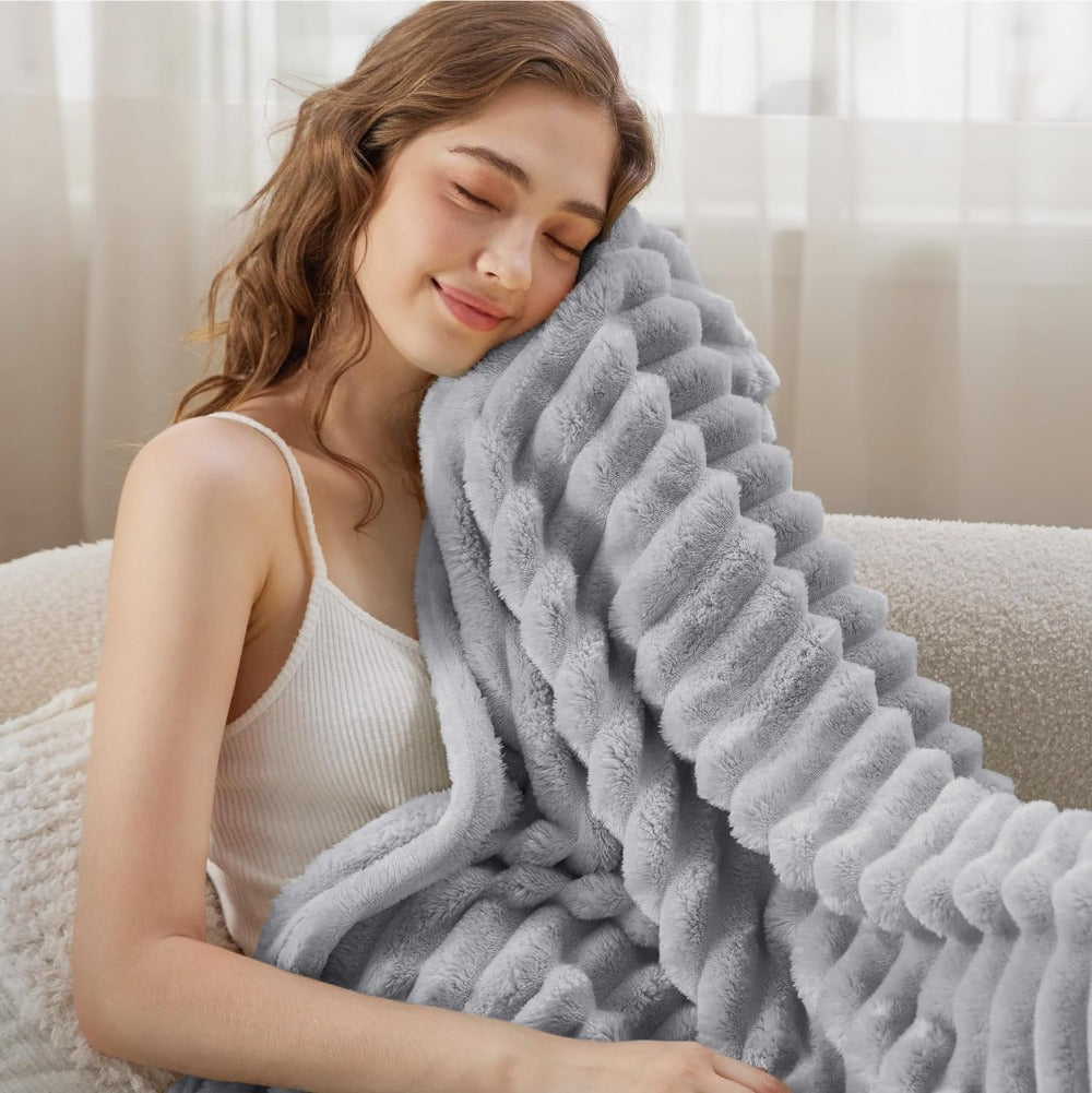 Woman wrapped in a fluffy gray blanket on a couch