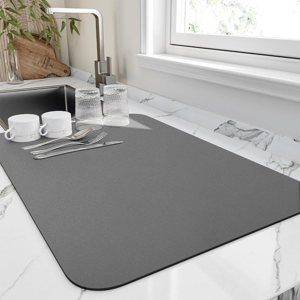 Gray placemat on a kitchen counter with cutlery and cups.
