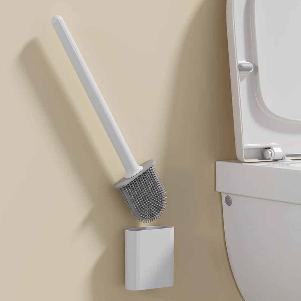 White toilet brush with holder against a beige wall next to a white toilet.