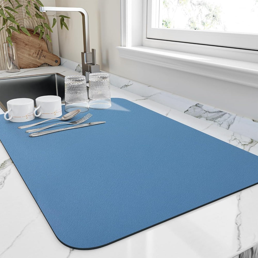 Blue placemat on a marble countertop with cutlery and cups.
