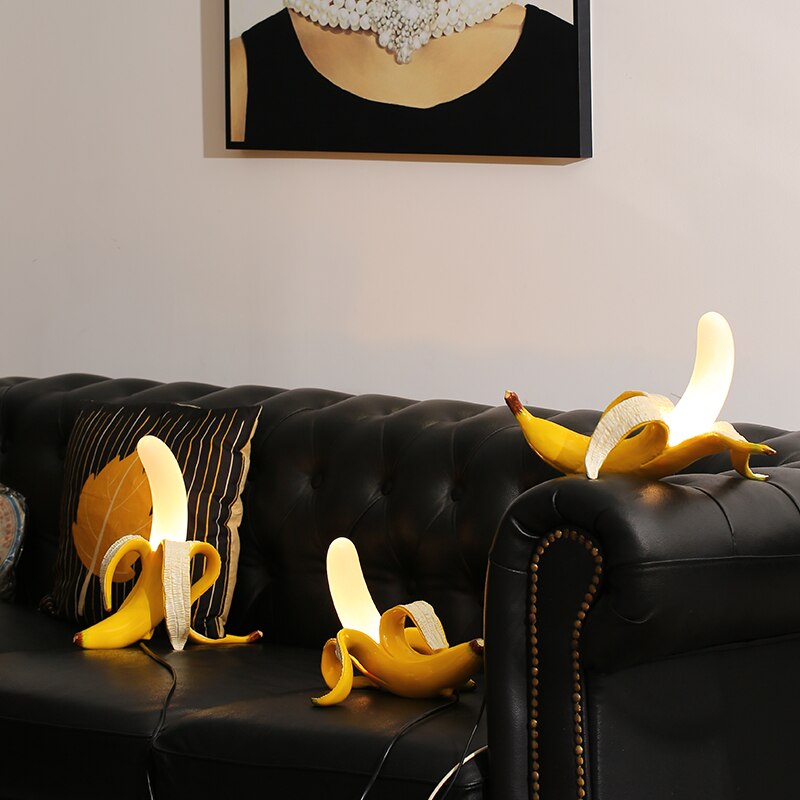 Banana peels on a black leather couch with a framed picture on the wall.