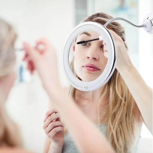 Woman applying mascara in front of a round makeup mirror with LED lights