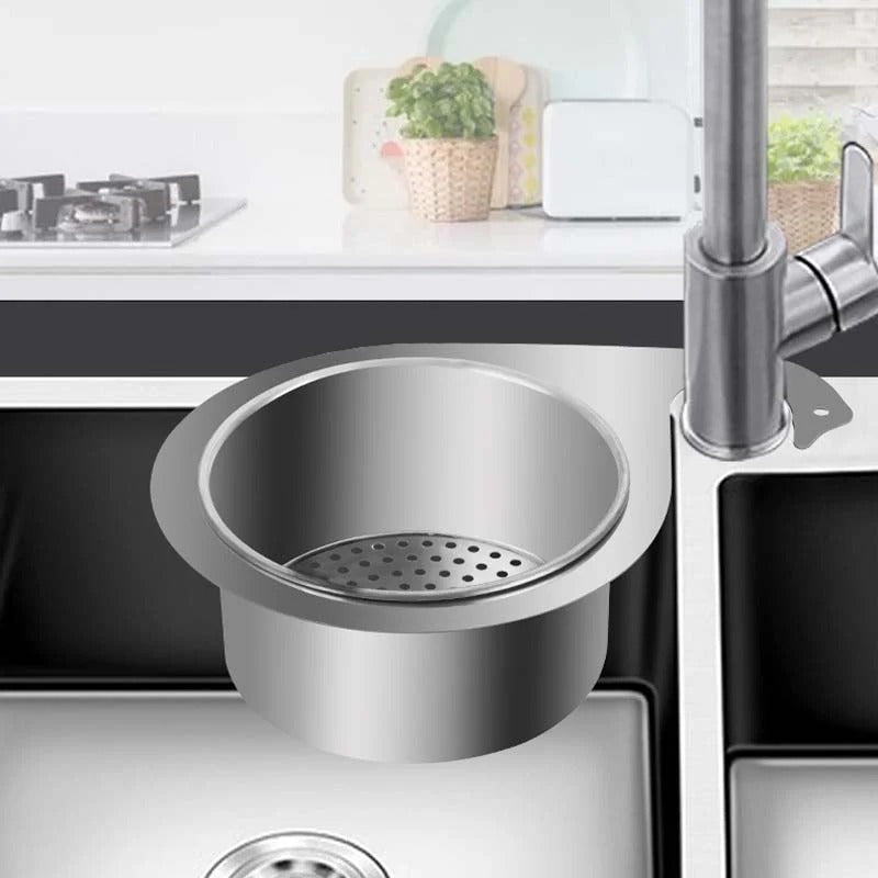 Stainless steel sink strainer in a kitchen setting with a faucet and countertop.