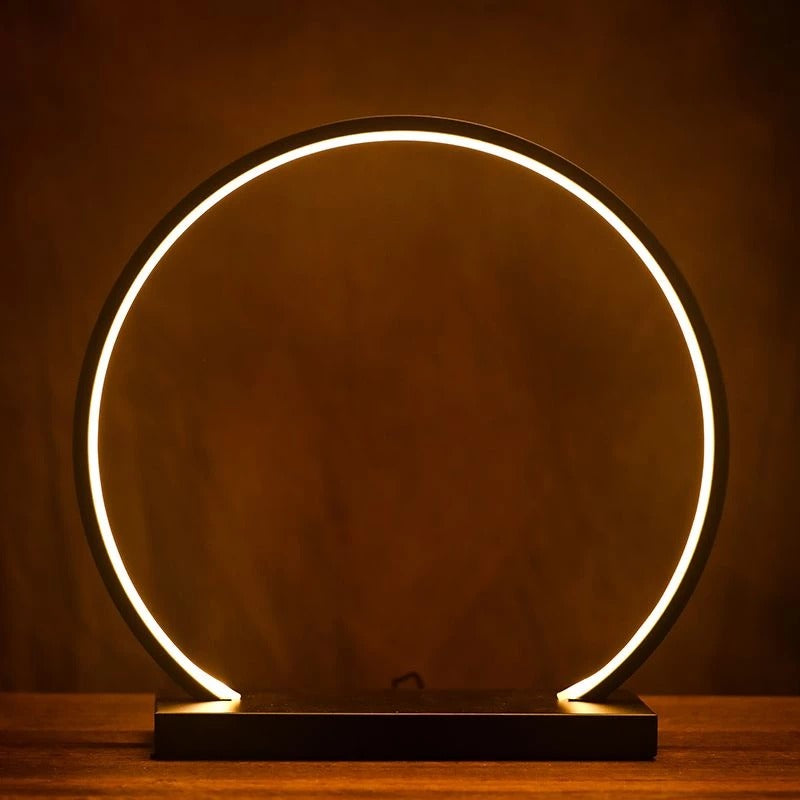 Modern circular light fixture on a wooden surface with a dark background