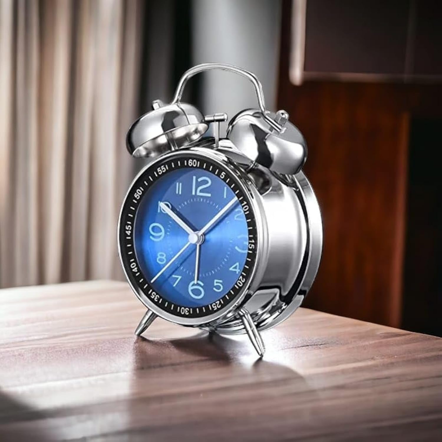 Silver alarm clock with a blue face on a wooden surface