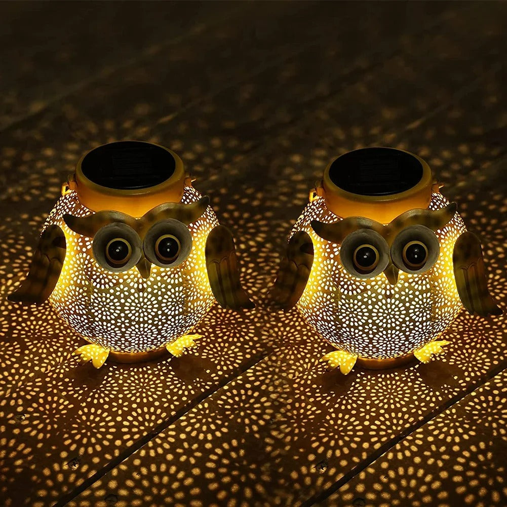 Two owl-shaped solar lights casting shadows on a dark surface