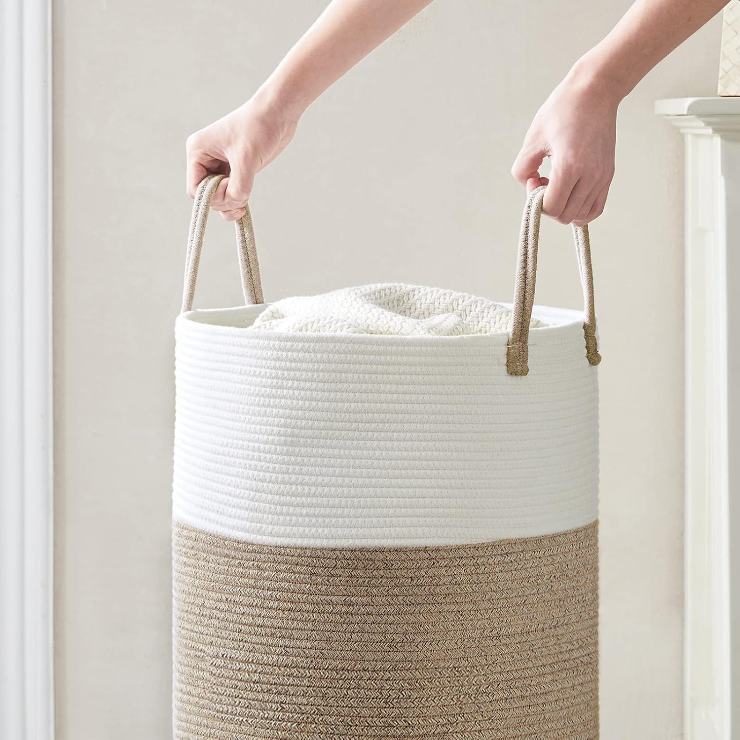 Person holding a white and beige woven basket with handles.