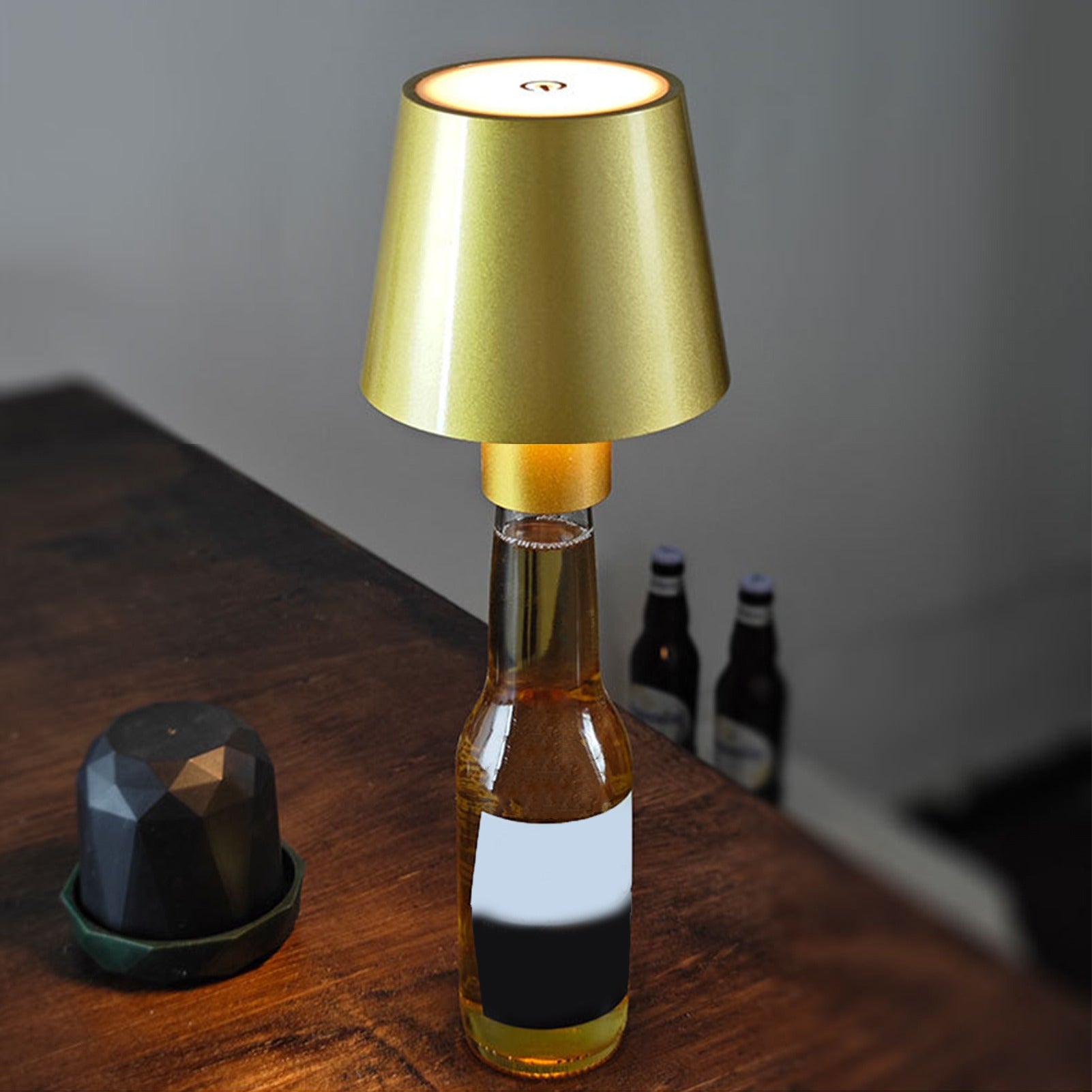 Bottle-shaped lamp with gold shade on a wooden surface