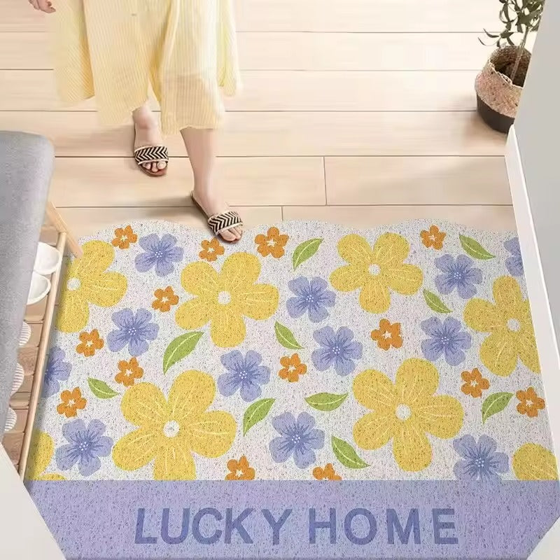 Floral patterned doormat with 'LUCKY HOME' text on a wooden floor.