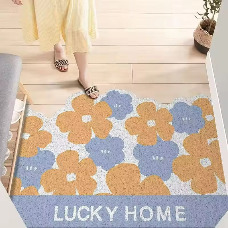 Floral patterned doormat with 'LUCKY HOME' text on a wooden floor.
