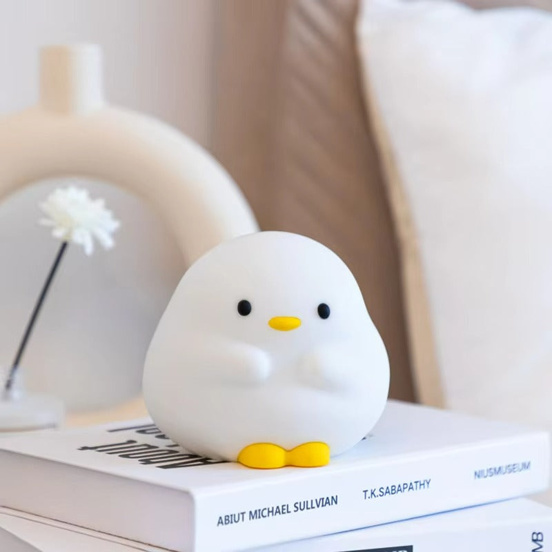 White duck-shaped toy on top of a book with a blurred background
