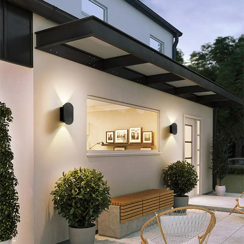 Modern outdoor setting with a wall-mounted television, plants, and seating area.