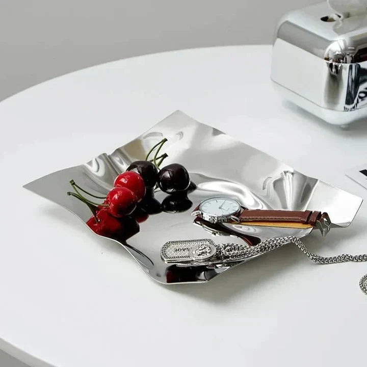 Silver tray with cherries, a watch, and a key on a white surface