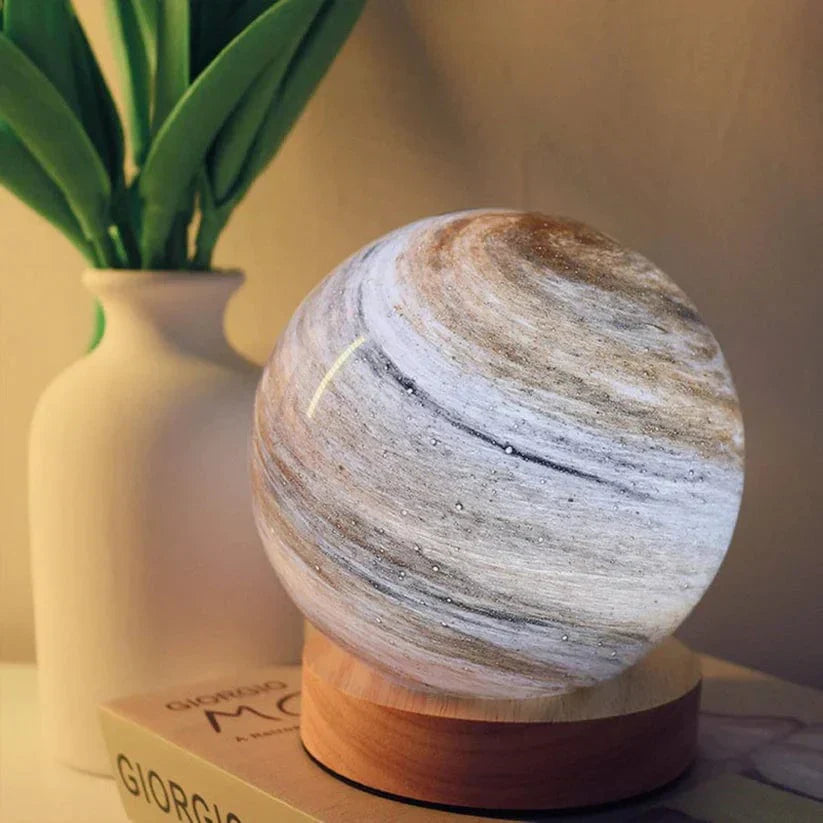 Marble-patterned lamp on a wooden base with a plant and book in the background