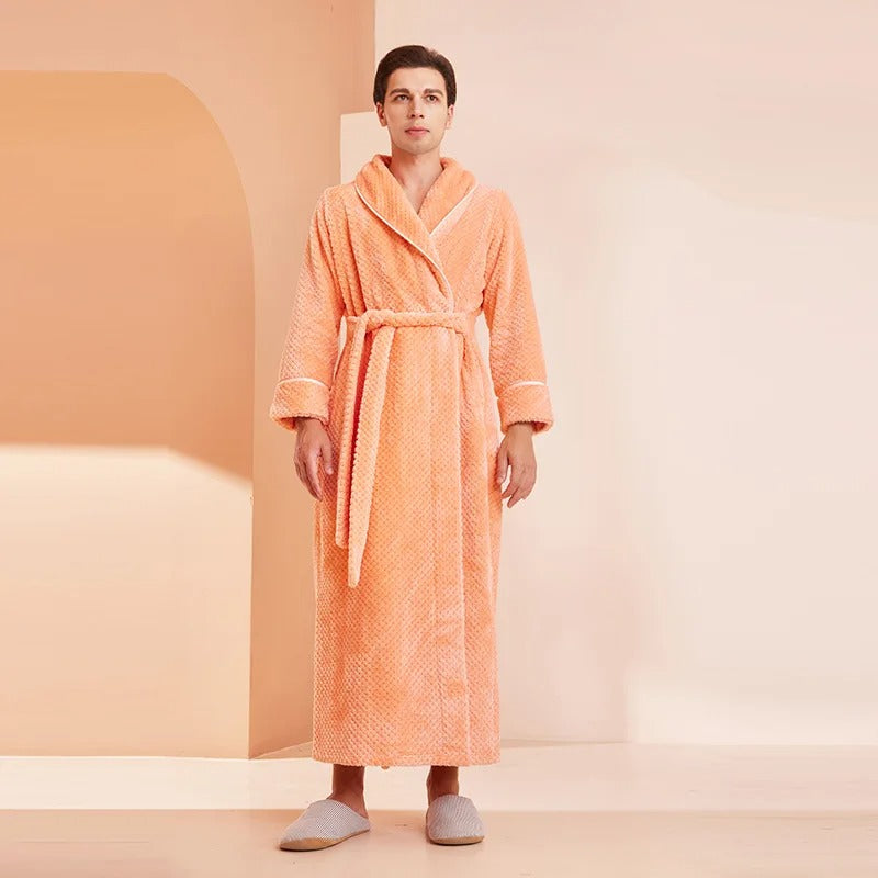 Woman wearing an orange bathrobe in a minimalistic room with a peach-colored wall.