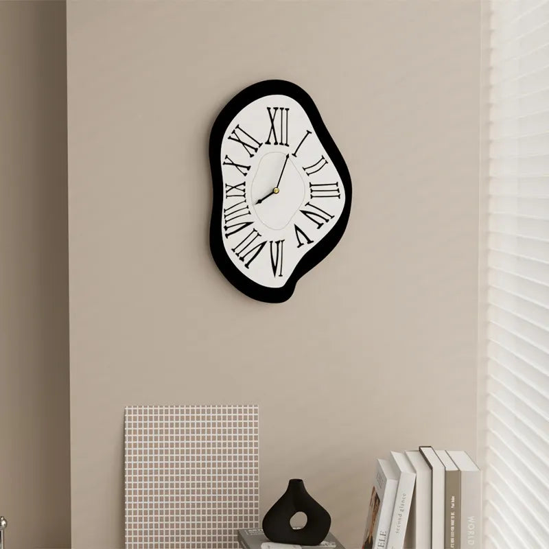 Modern wall clock on a beige wall with books and decor items below.