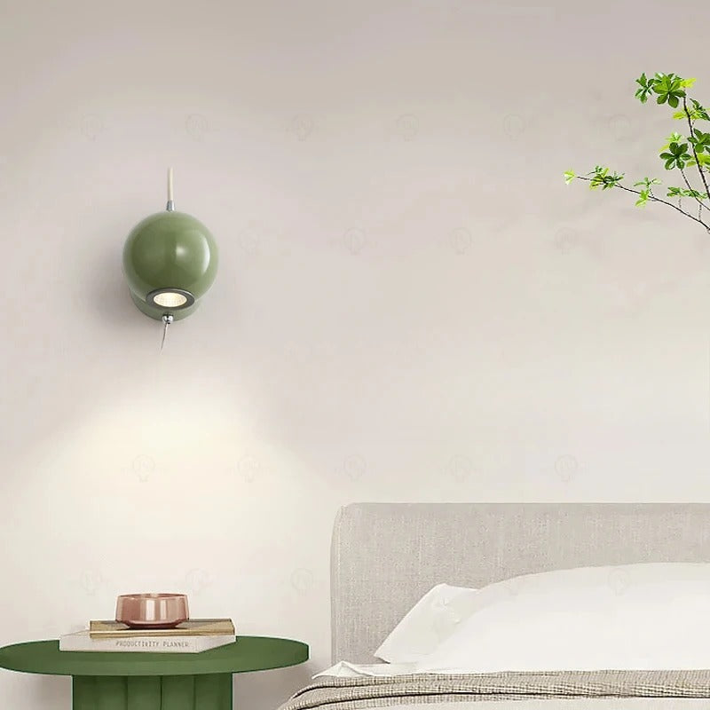 Green pendant light above a bed with a side table in a bedroom setting