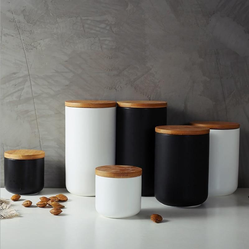 Set of cylindrical storage jars with wooden lids on a gray surface.