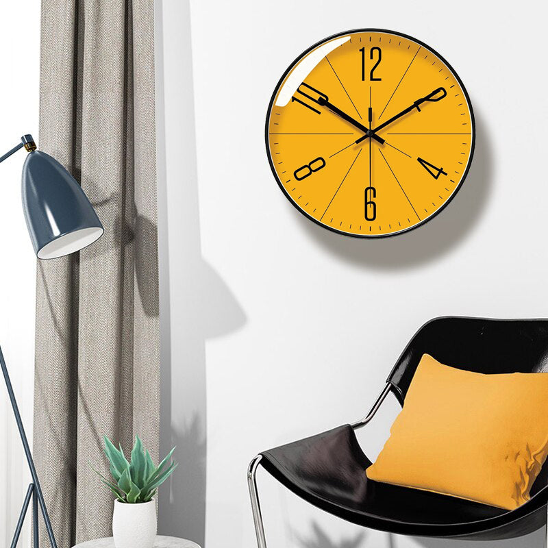 Yellow wall clock on a white wall with a black chair and plant in the foreground