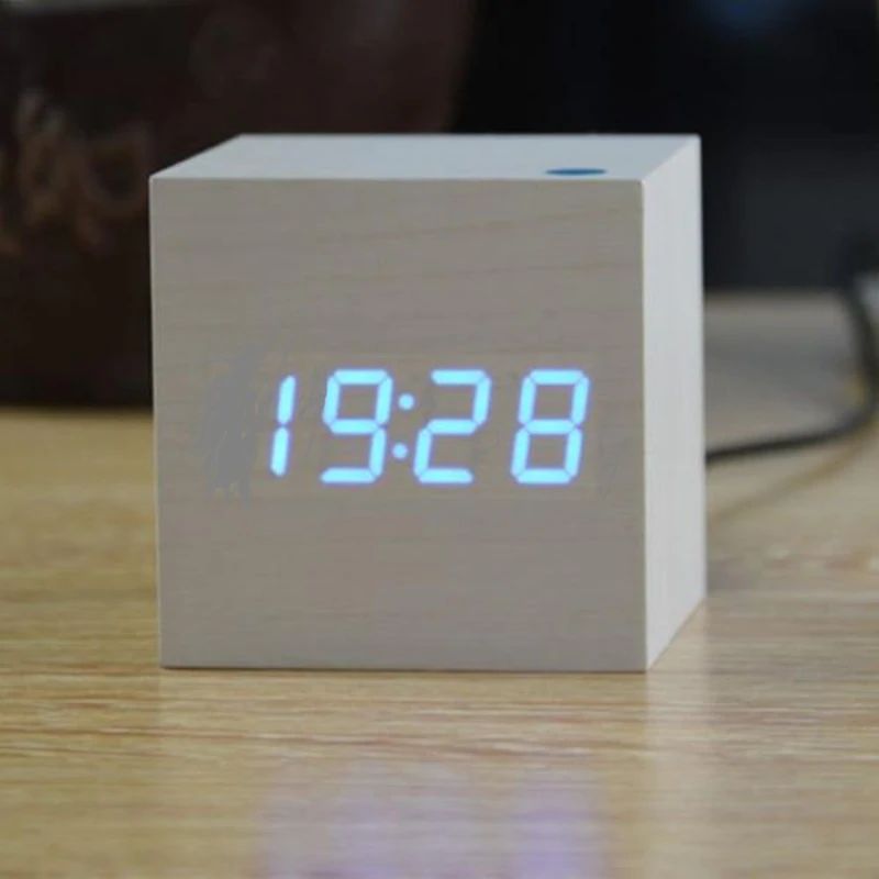 Wooden cube clock with digital time display on a wooden surface