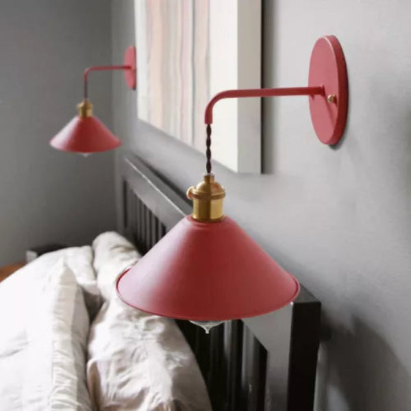Red wall-mounted lamp with gold fixture on a white wall.