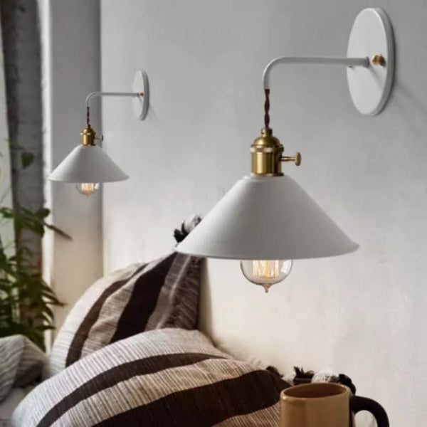 Two wall-mounted lamps with white shades and brass fixtures on a light gray wall.