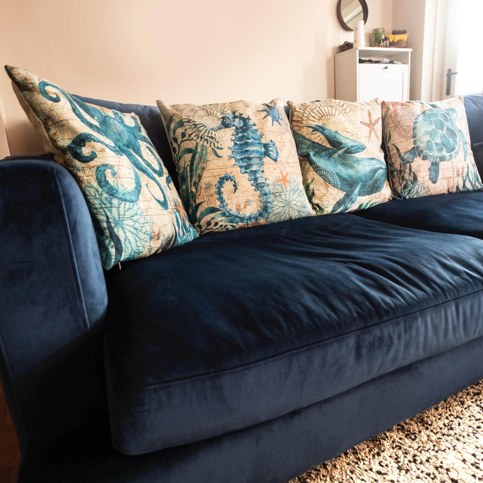 Navy blue sofa with decorative pillows featuring marine life patterns in a living room setting.
