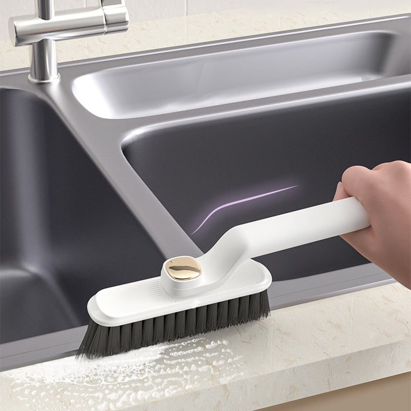 Cleaning brush being used on a kitchen counter next to a sink.
