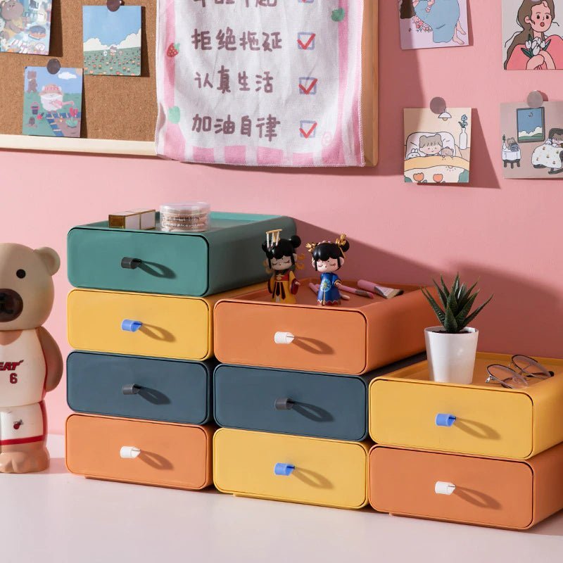 Colorful storage drawers with small figurines and a plant on a pink wall background