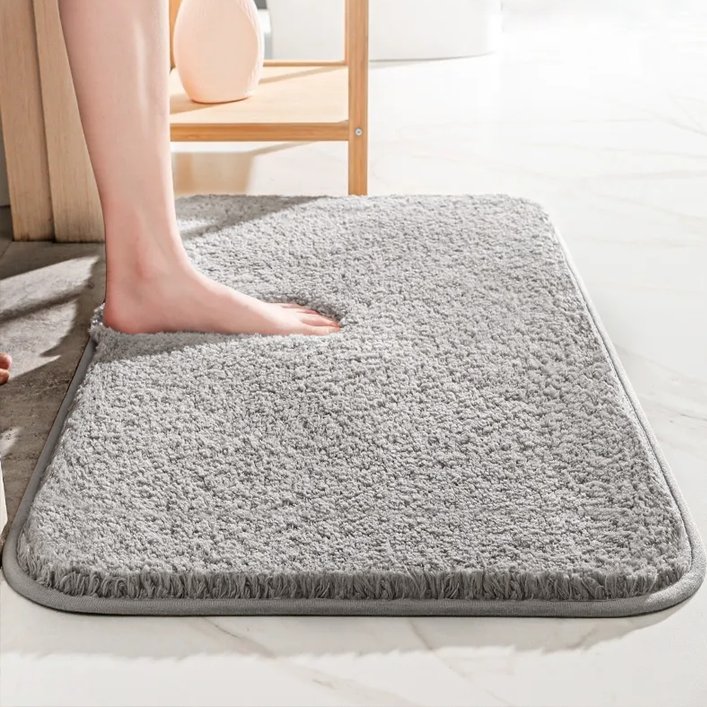 Gray textured bath mat on a white surface with a blurred background
