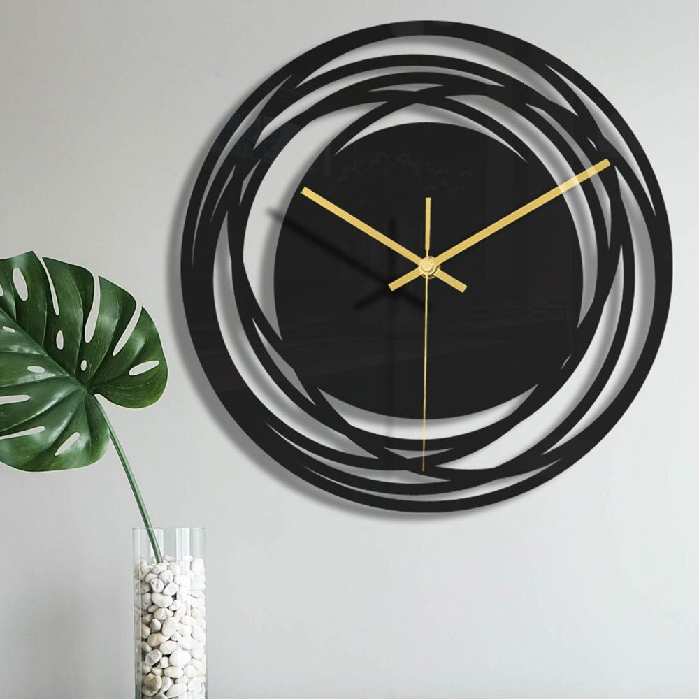 Modern wall clock with black circular design and gold hands on a light gray background.